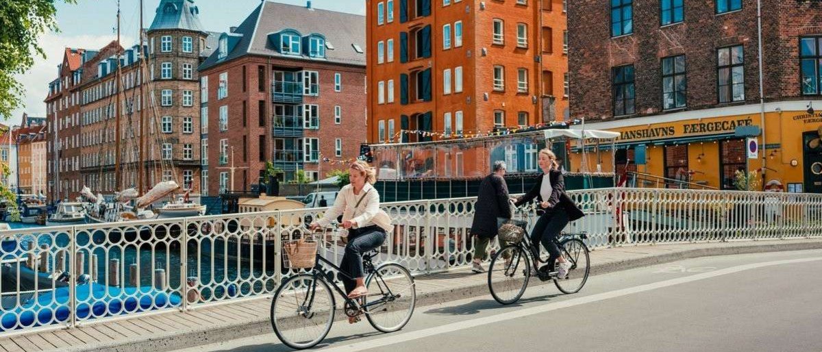 Two people riding their bicycles on a bridge in Copenhagen