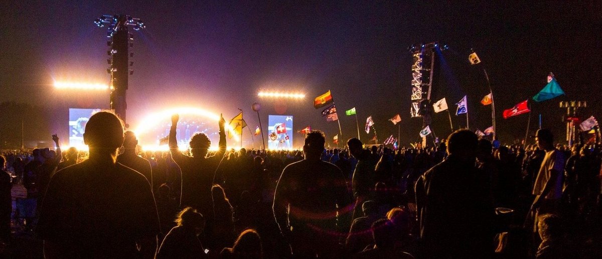 A crowd of people at a concert waving flags