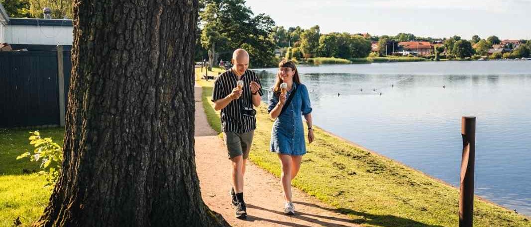 A couple eating ice cream while walking next to a lake