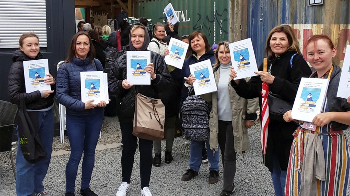 A group of Ukrainian refugees holding printed versions of af Dansih-Ukranian-English dictionary