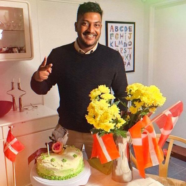 Man standing next to a table celebrating his birthday with Danish flags all over