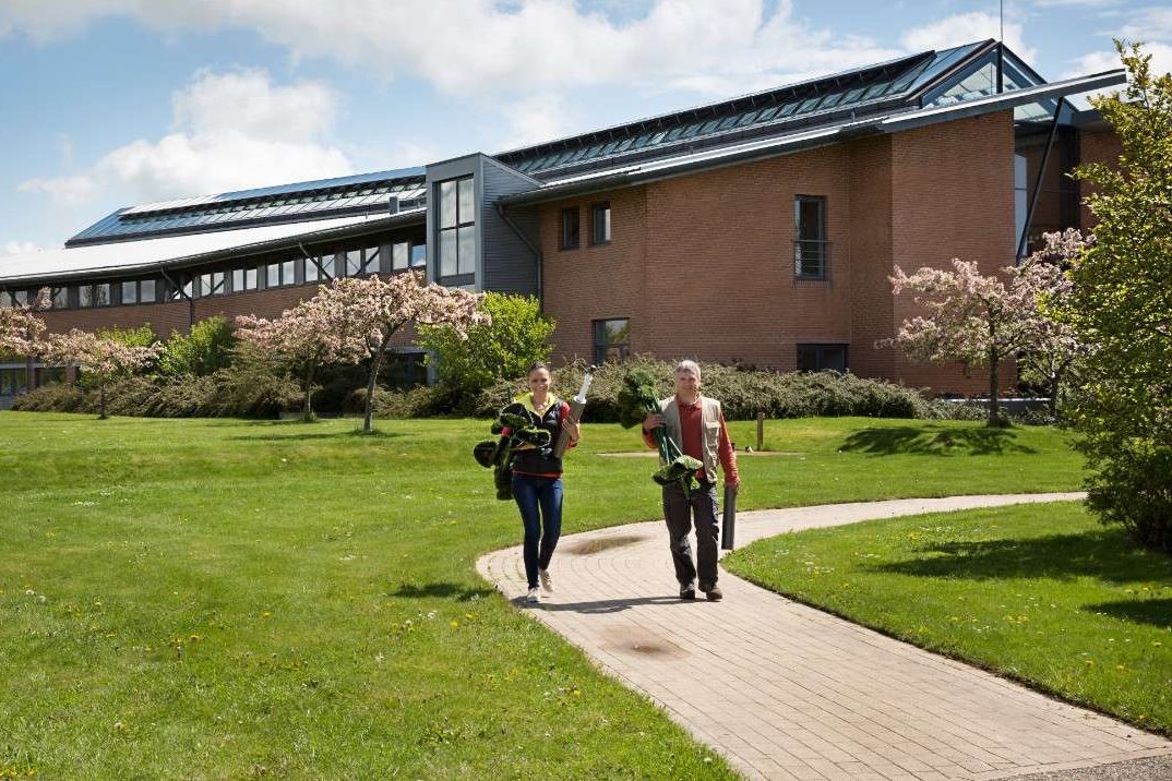 Two people walking in front of the Aarhus University Flakkebjerg building