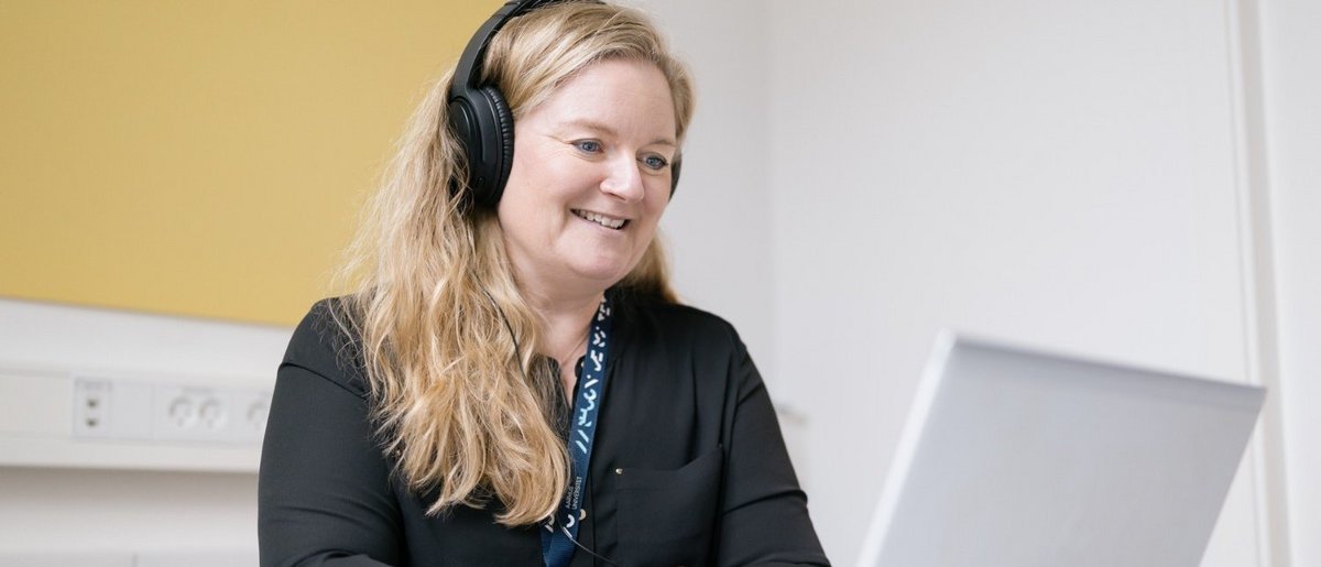 A woman sitting in front of a computer with a headset on