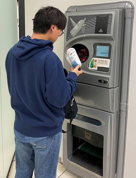 A person throwing a pant bottle into a pant machine