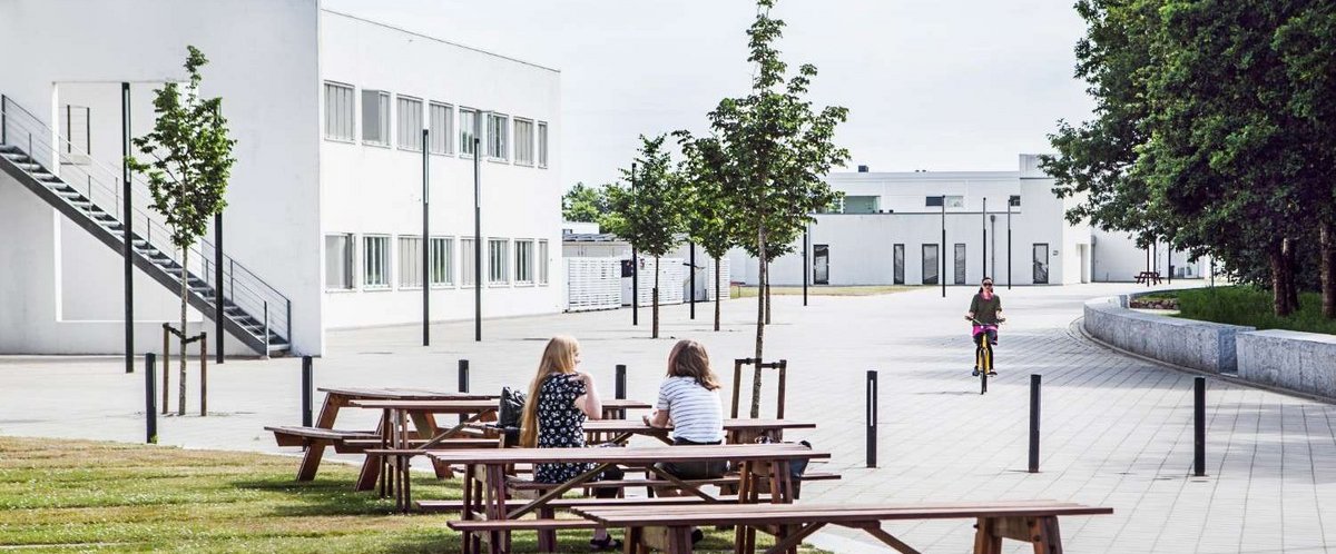 Aarhus University Herning building with people sitting on benches outside