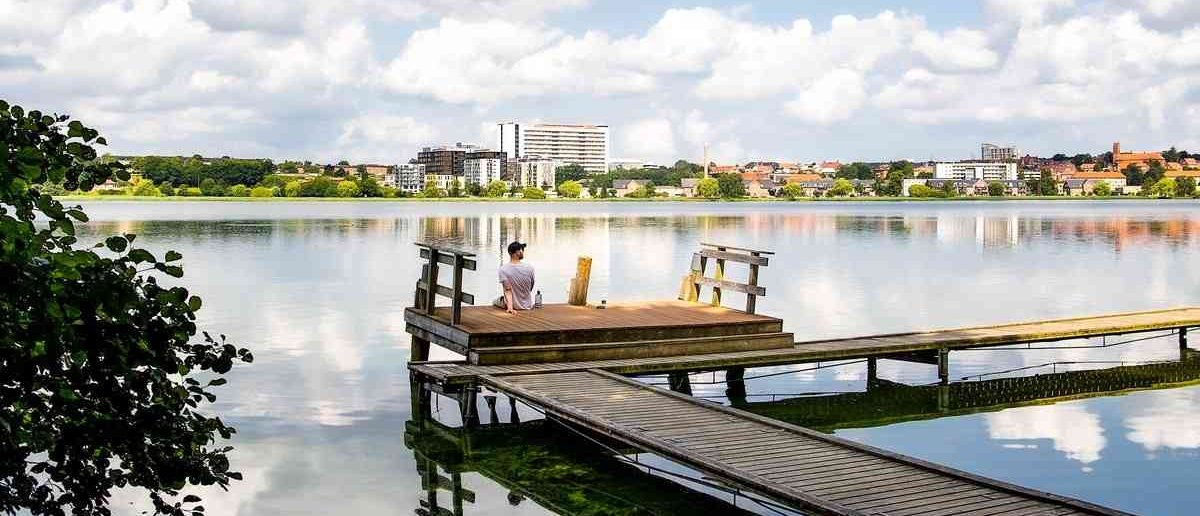 Man sitting on the edge of a swimming pier overlooking a town
