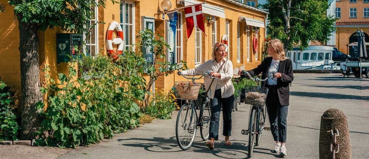 Two people walking with their bicycles in a street in Copenhagen