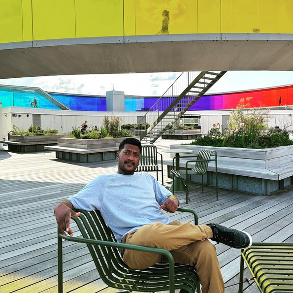 Man sitting on a bench in front or a glass rainbow walkway