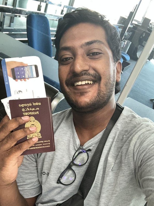 Man taking a selfie, holding his passport next to his face.