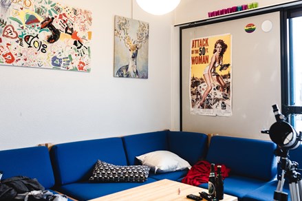A comunal space with a blue sectional couch and posters on the wall